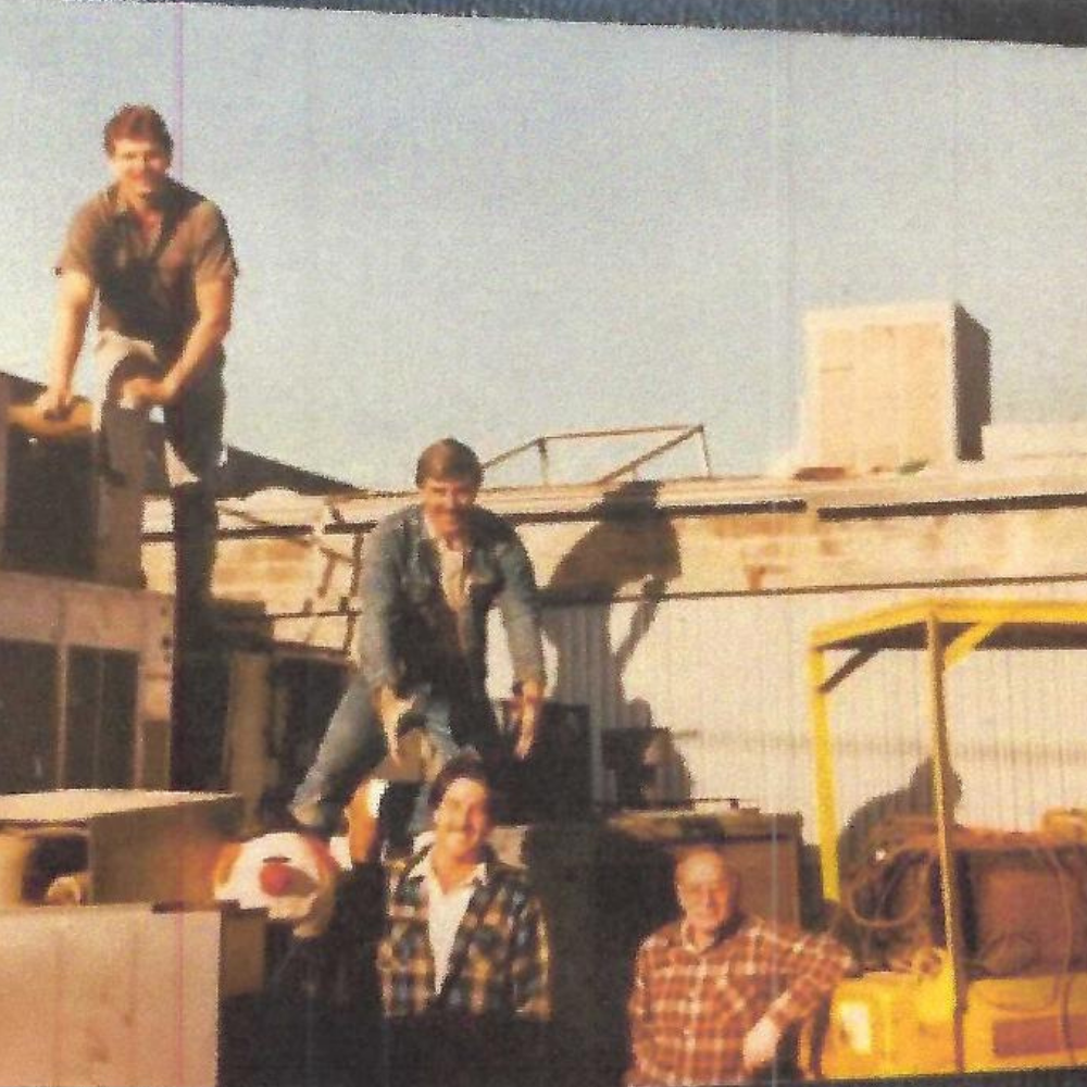 a group of men standing on top of an AC truck.