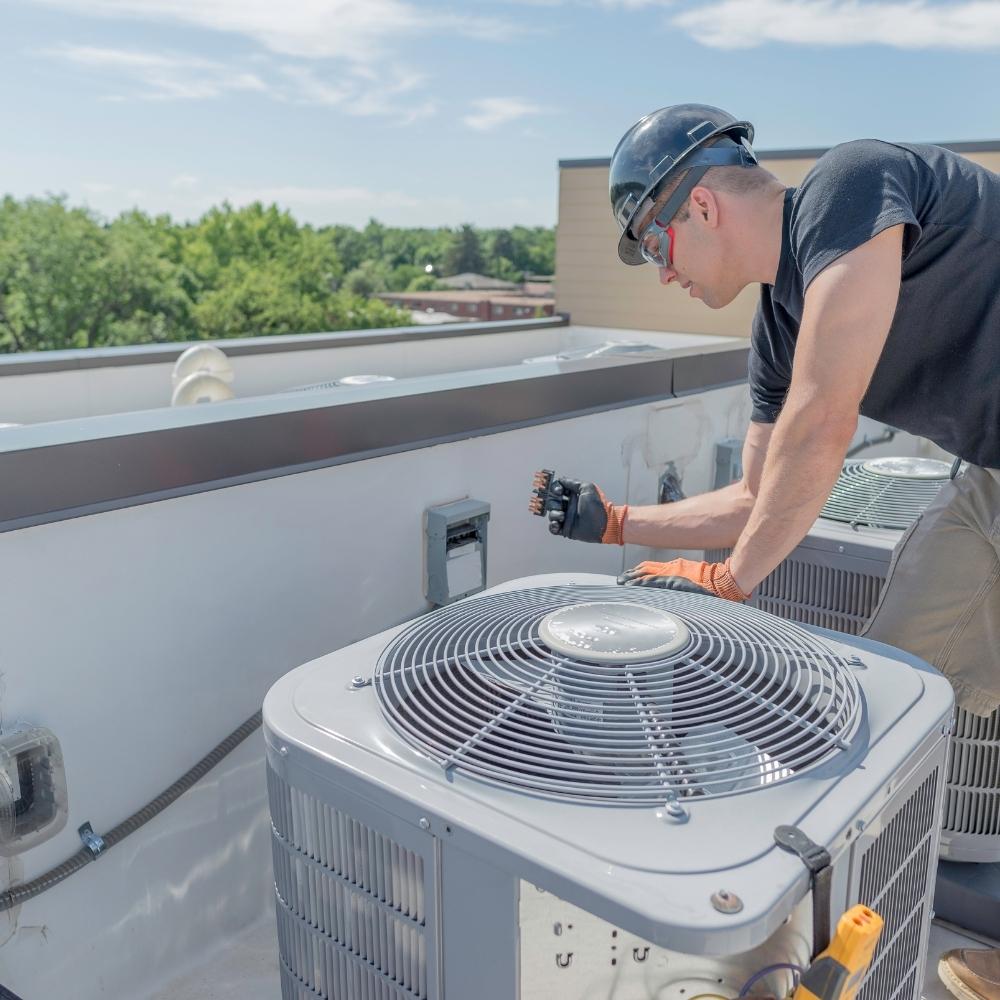 A member working on an air conditioner on a roof.